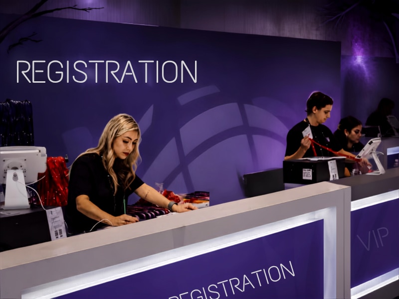 Event staff assisting attendees at the registration counter