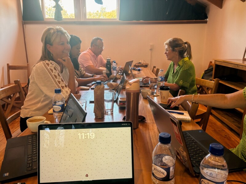 Team members collaborating on laptops around a conference table during a working session.