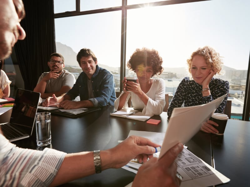 Group of colleagues in a meeting room engaged in discussion.