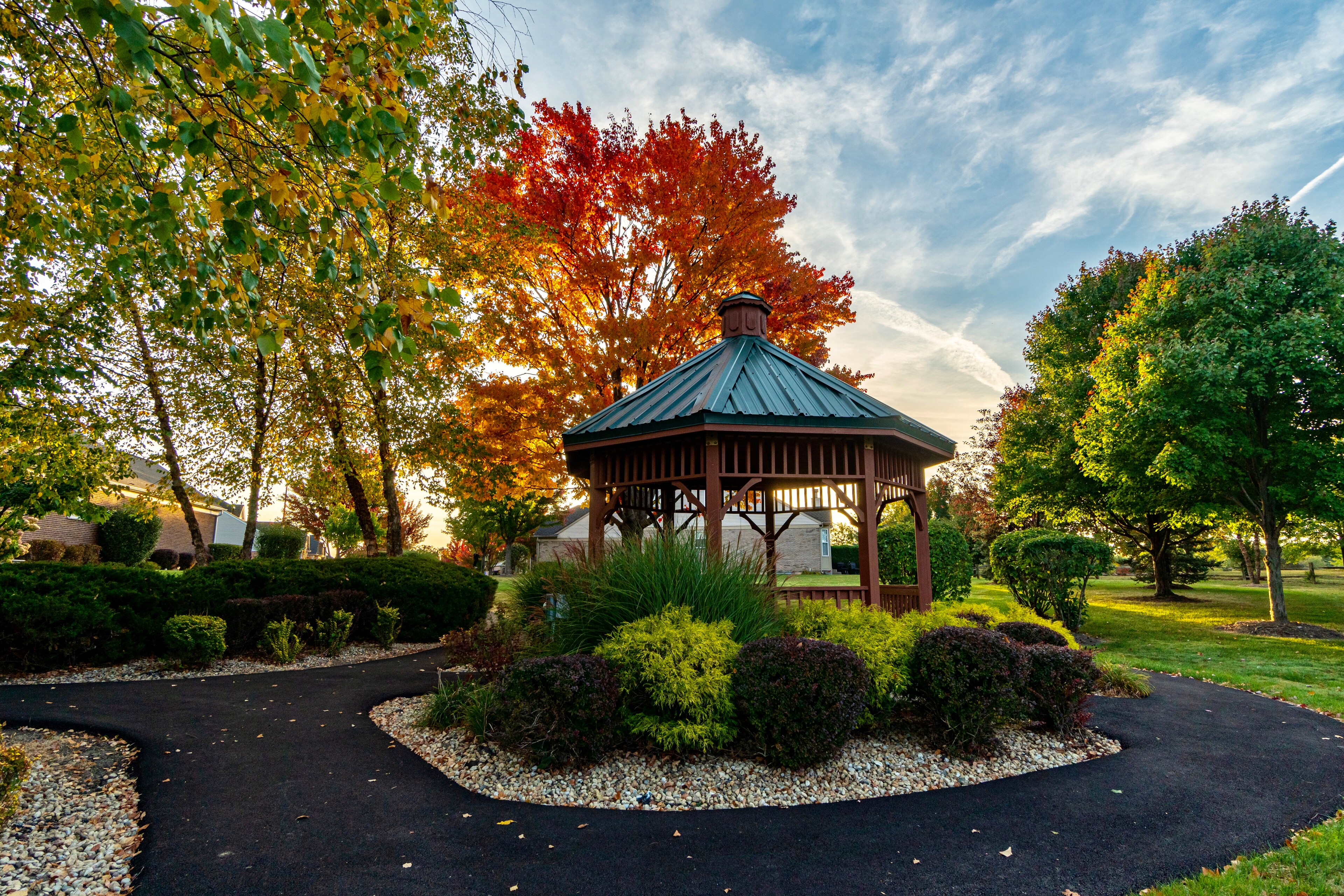 A gazebo surrounded by colorful autumn trees in a peaceful park setting.