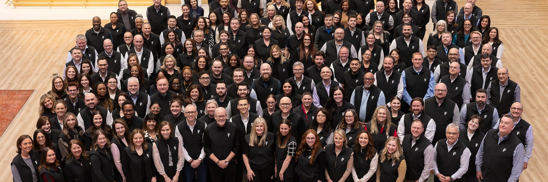 A group of people in black vests standing in a large room