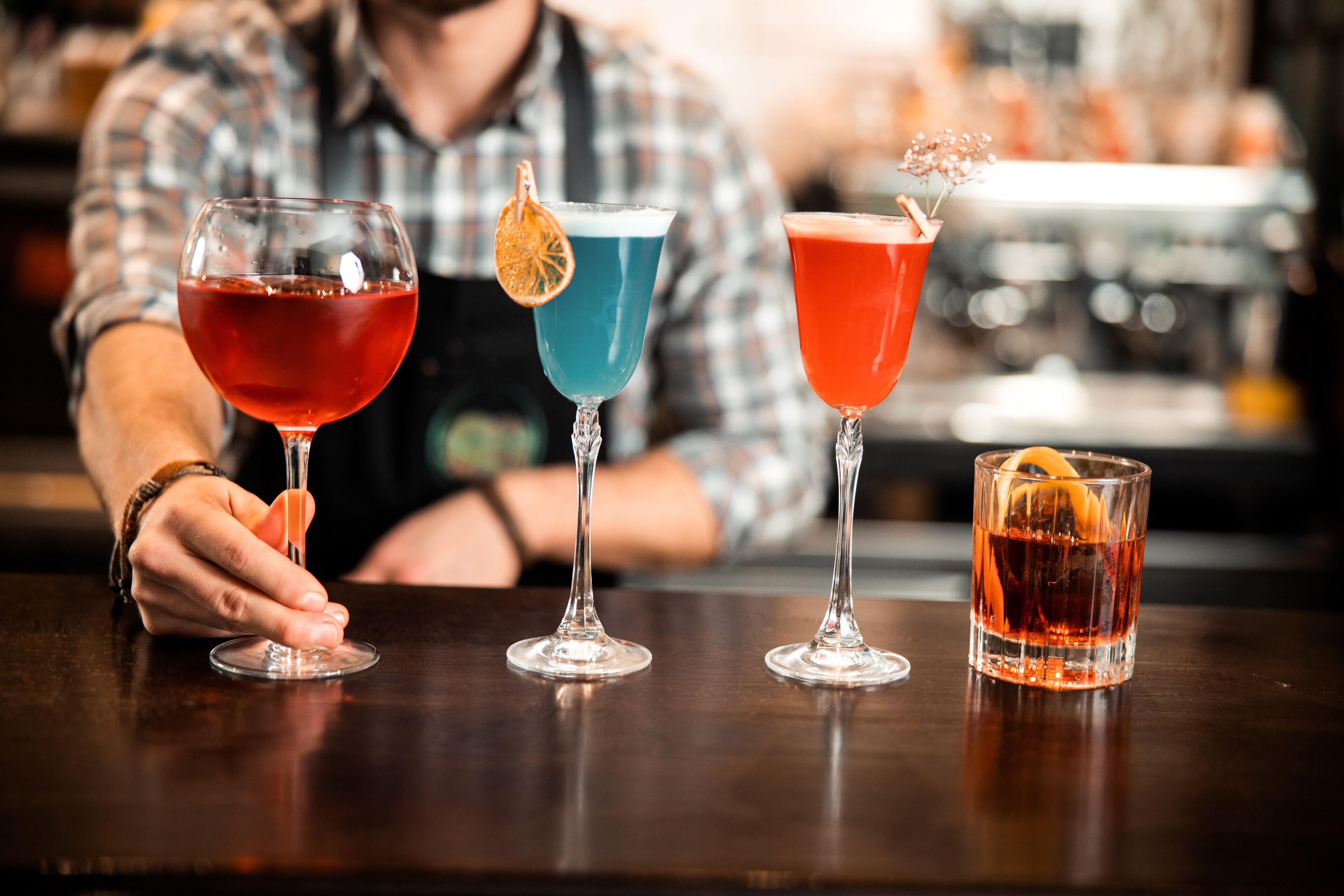 A man is holding a glass of different colored drinks