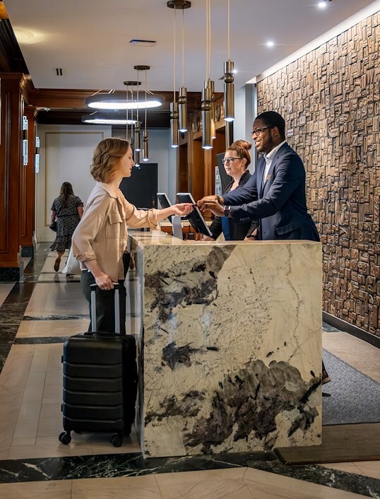 A woman with a suitcase checks in at a hotel front desk