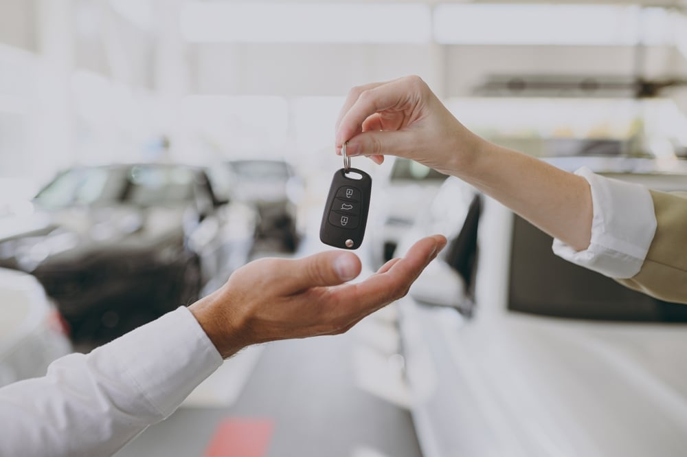 Car salesperson handing over the keys to a new car