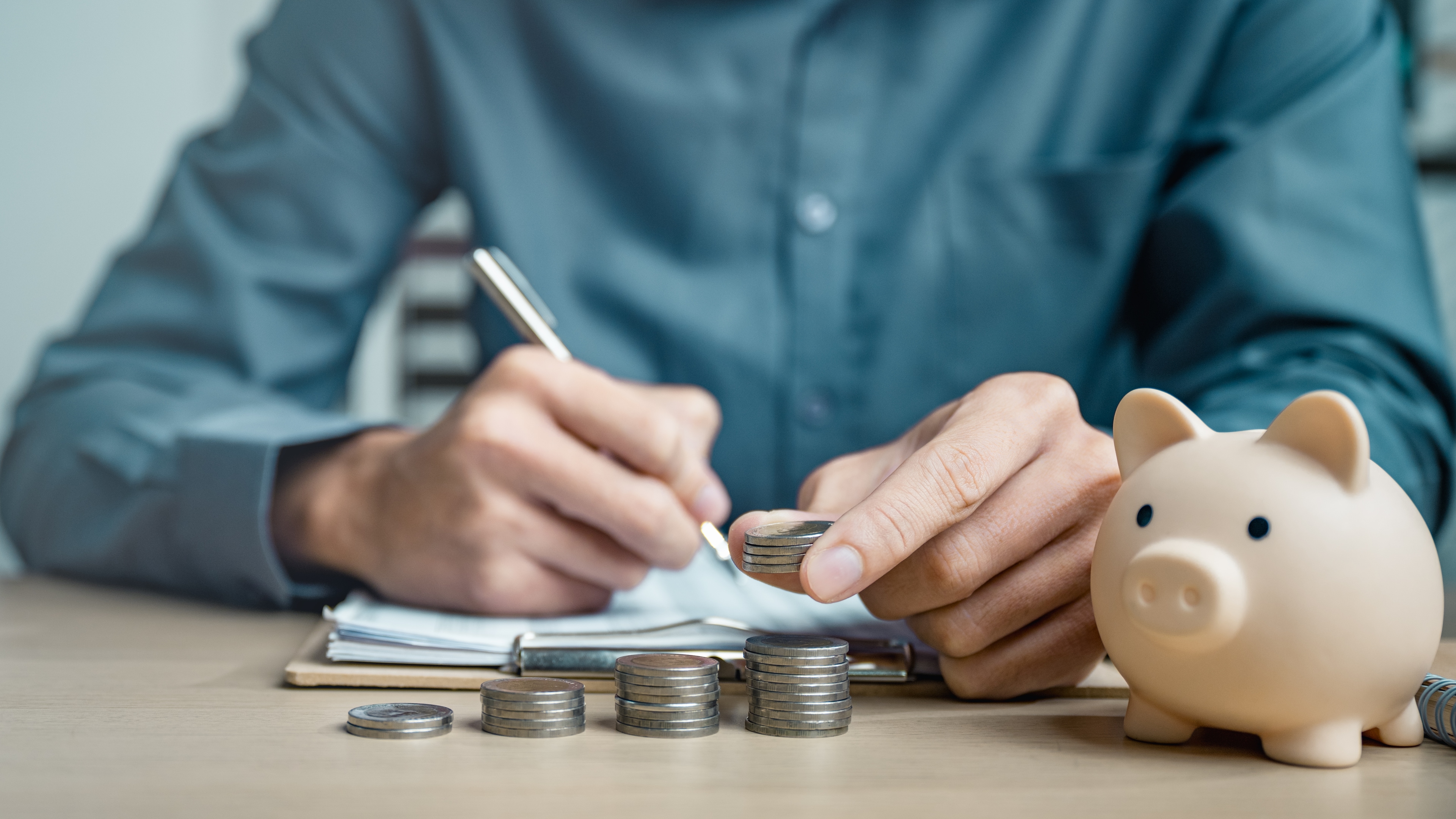 Man stacking coins next to piggy bank