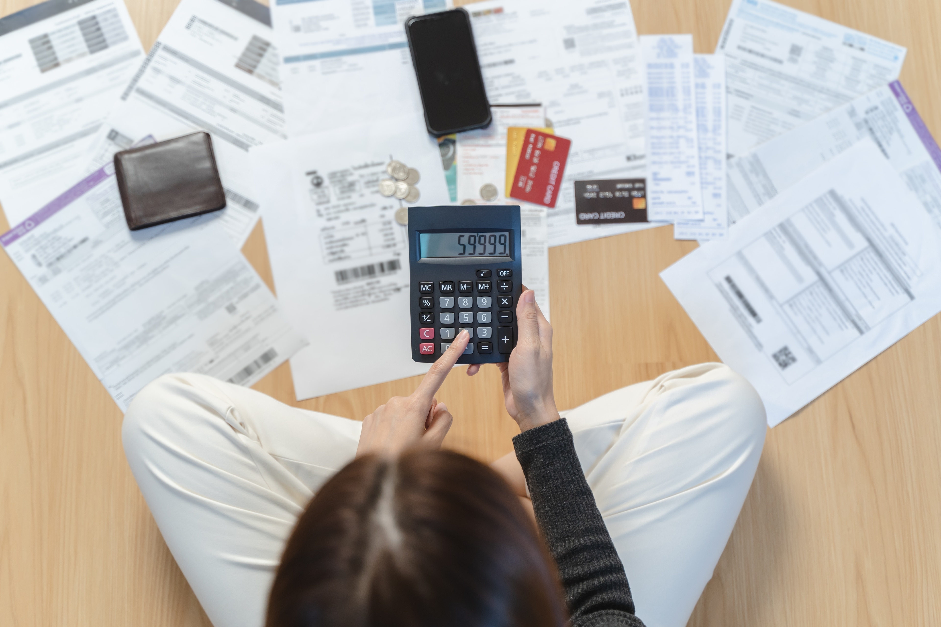 Woman calculating credit card debt with bills in the background
