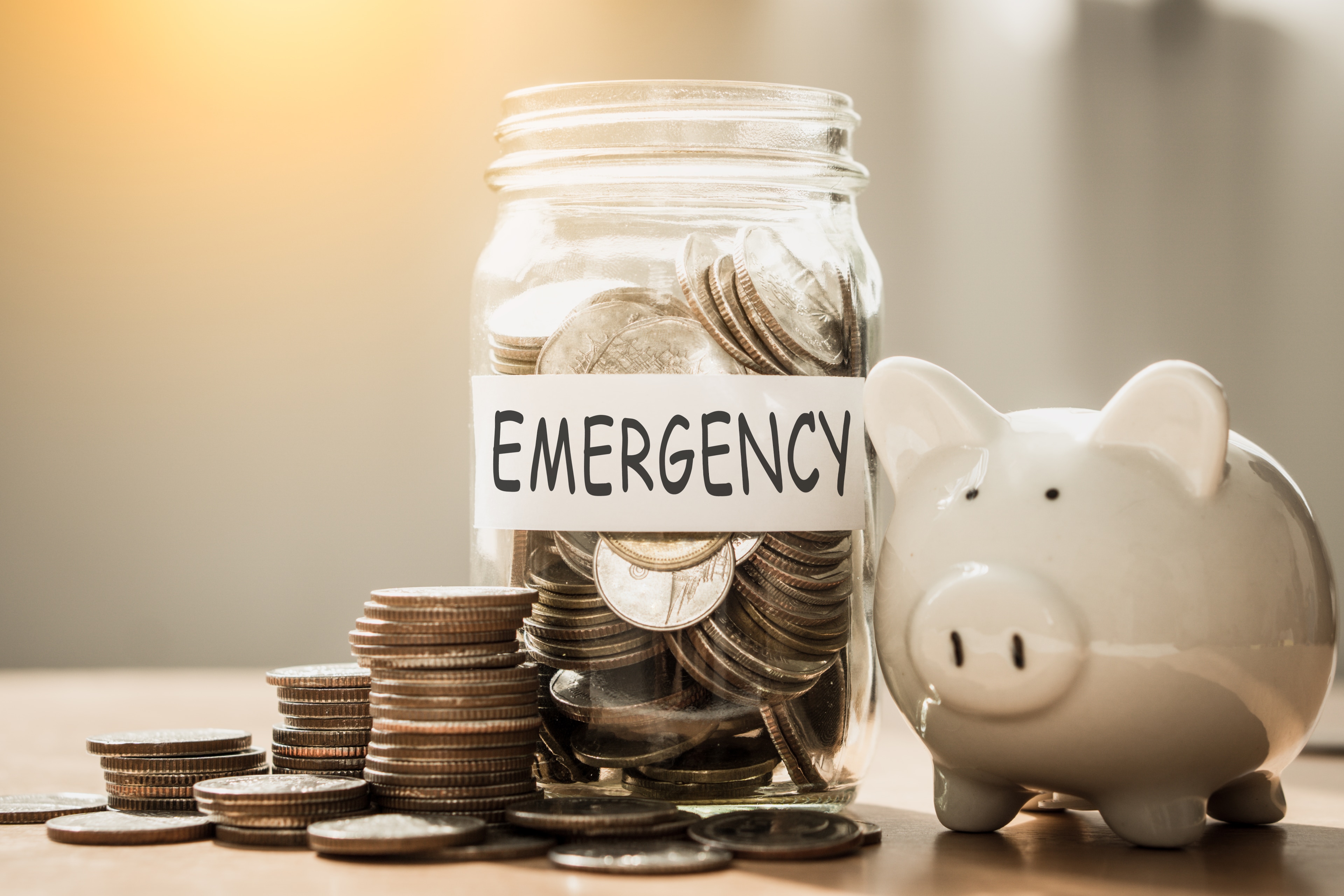 Piggy bank and jar full of coins with emergency written on it