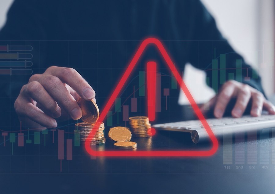 Warning sign over stacked coins representing investment and cryptocurrency scams