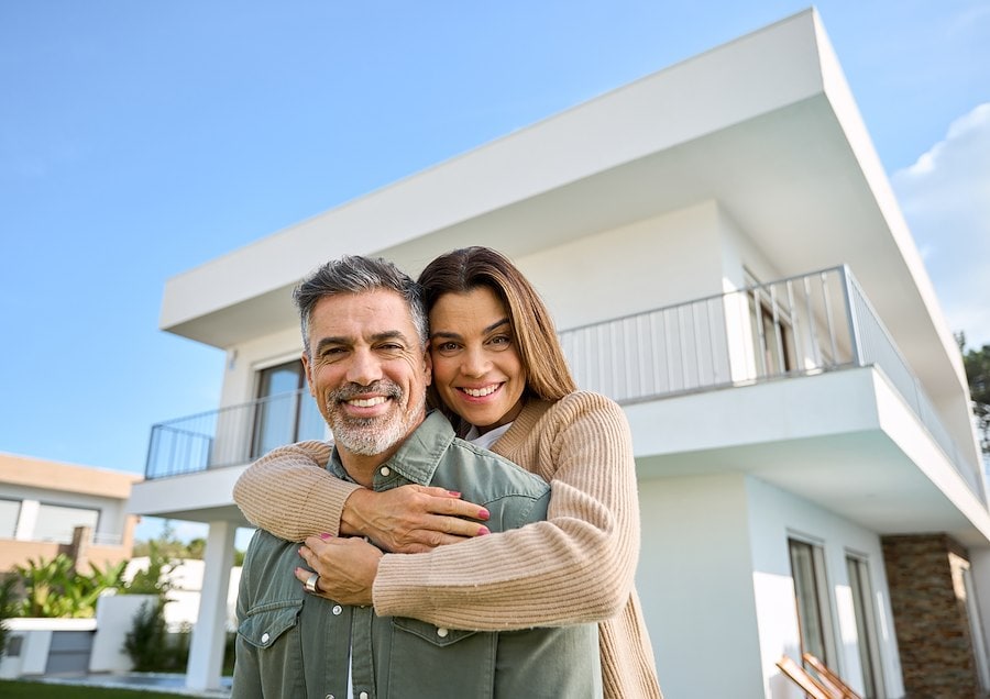 Happy couple in front of their new home.