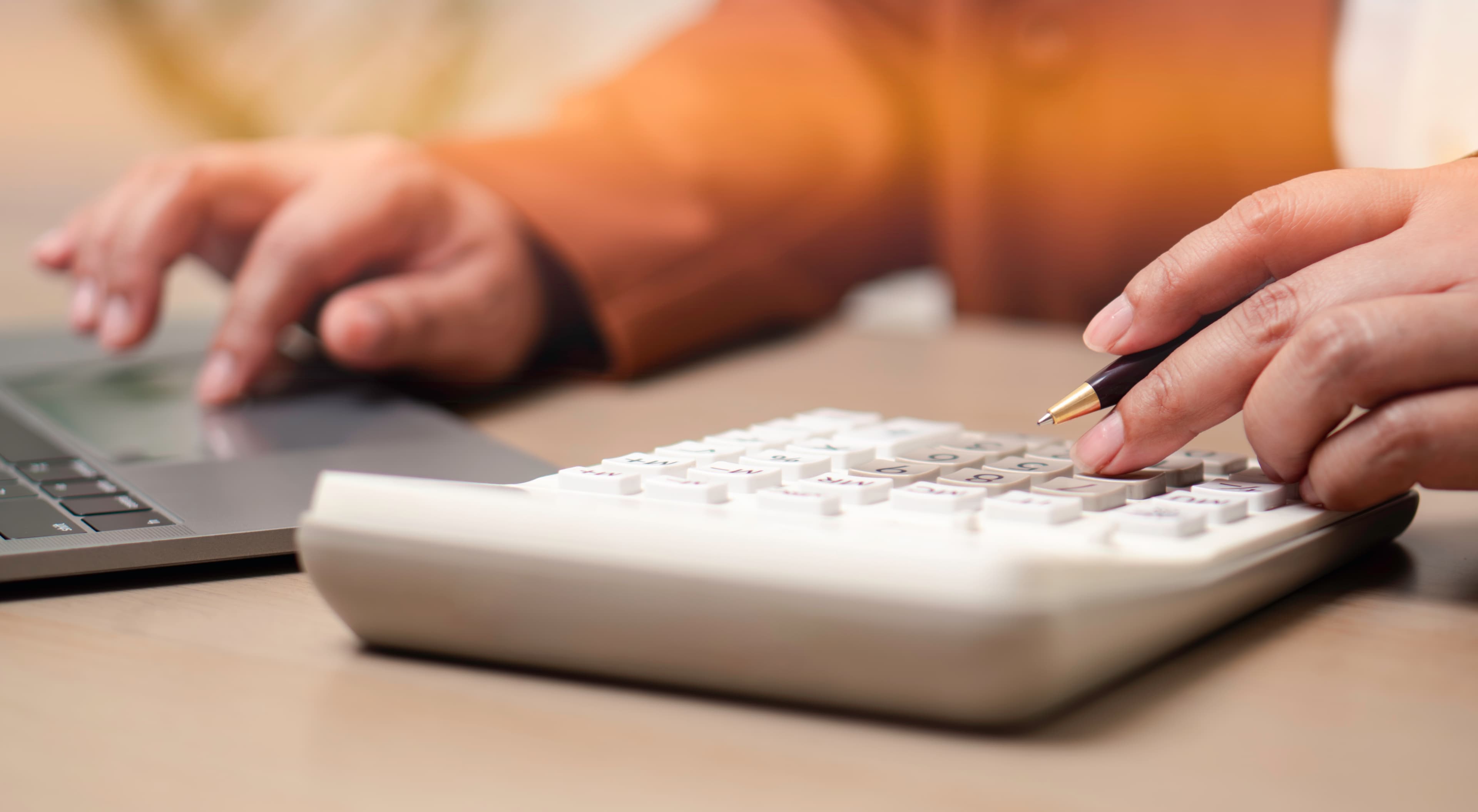 person using calculator and laptop to manage budget