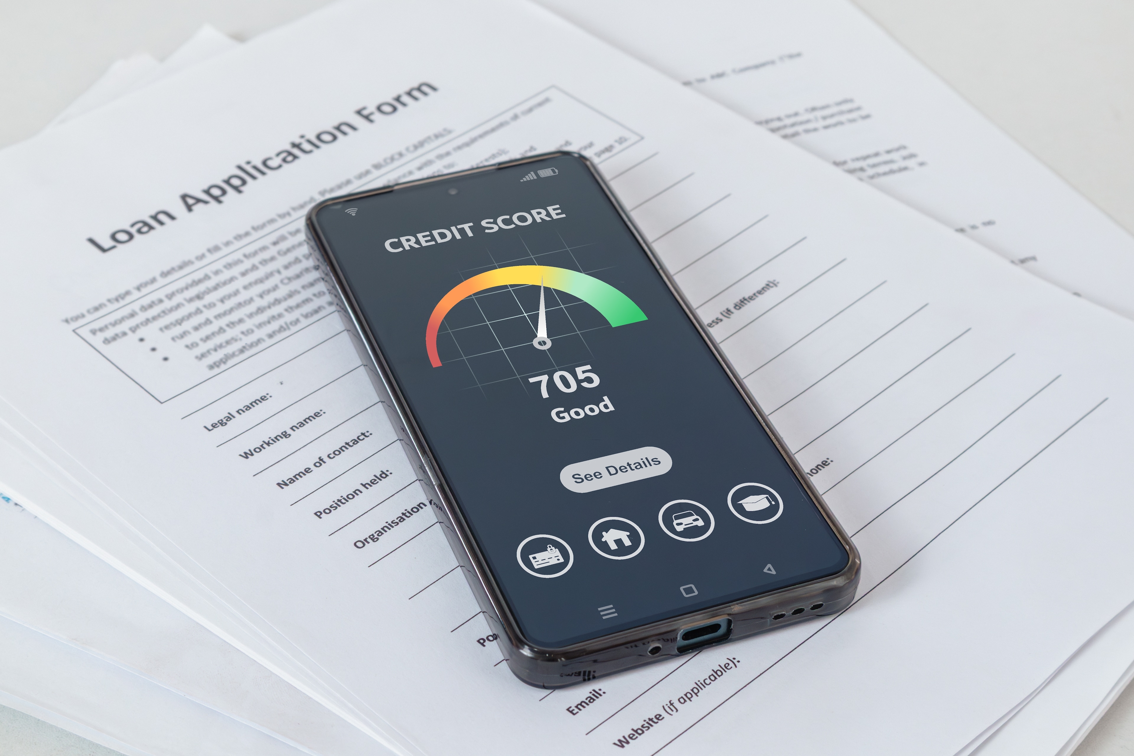 Phone showing credit score on top of debt consolidation loan application form.
