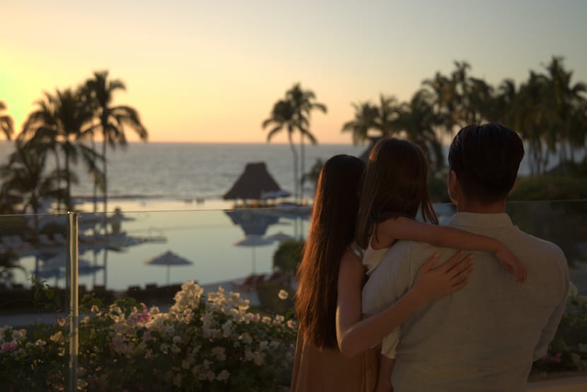 A man and two girls hugging and looking at the ocean