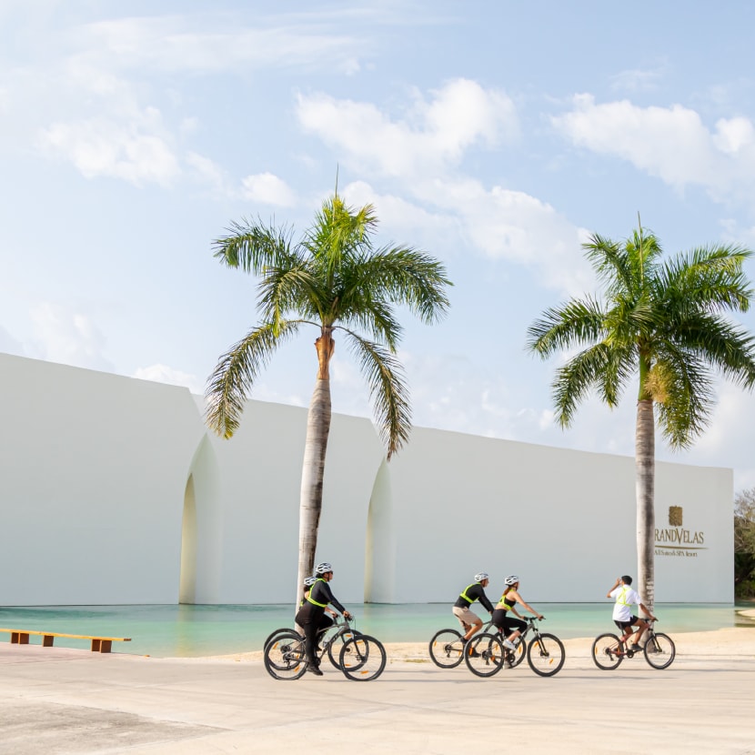 A group of people riding bicycles in front of a white building