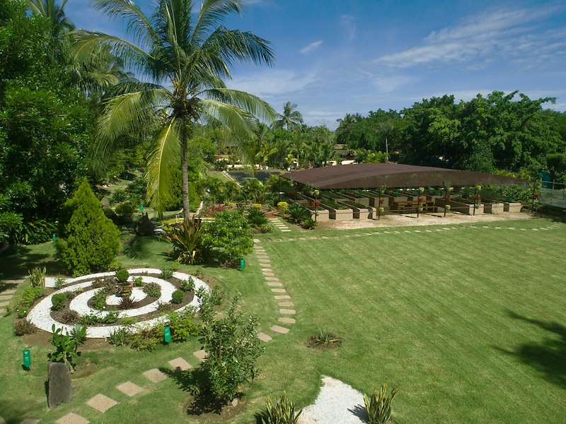 Tropical botanical garden at Casa Velas resort featuring sustainable herb gardens, manicured lawns, and palm trees in a serene landscape design.