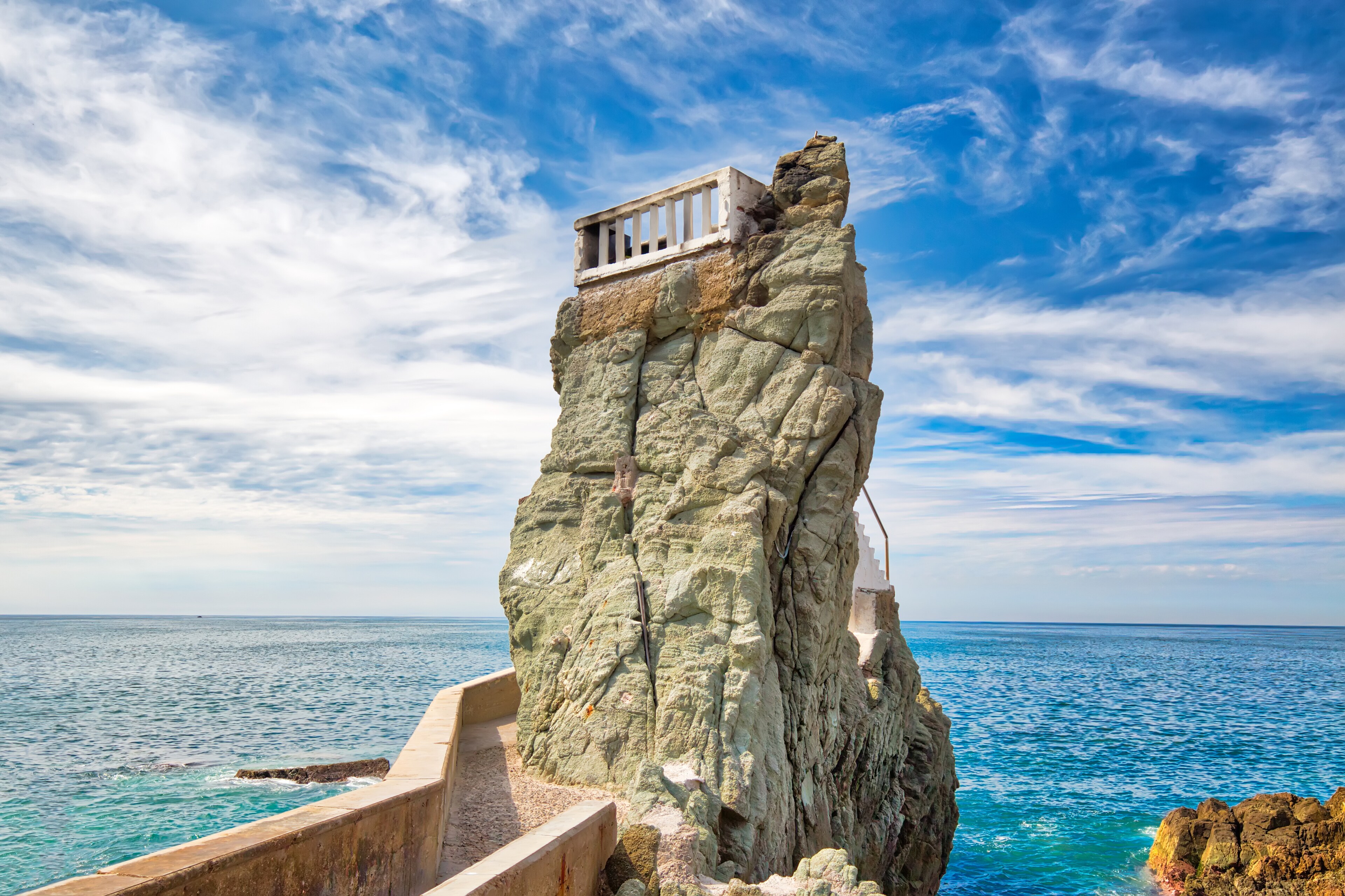 A small house on top of a rock near the ocean