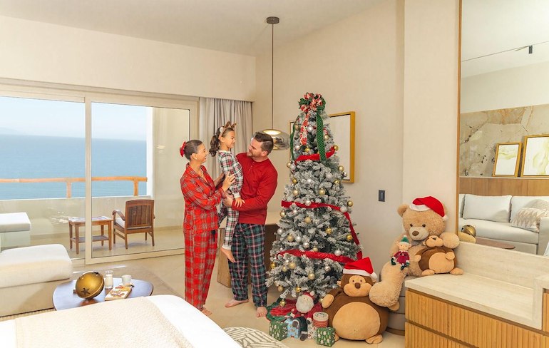 A man holding a child in pajamas next to a christmas tree