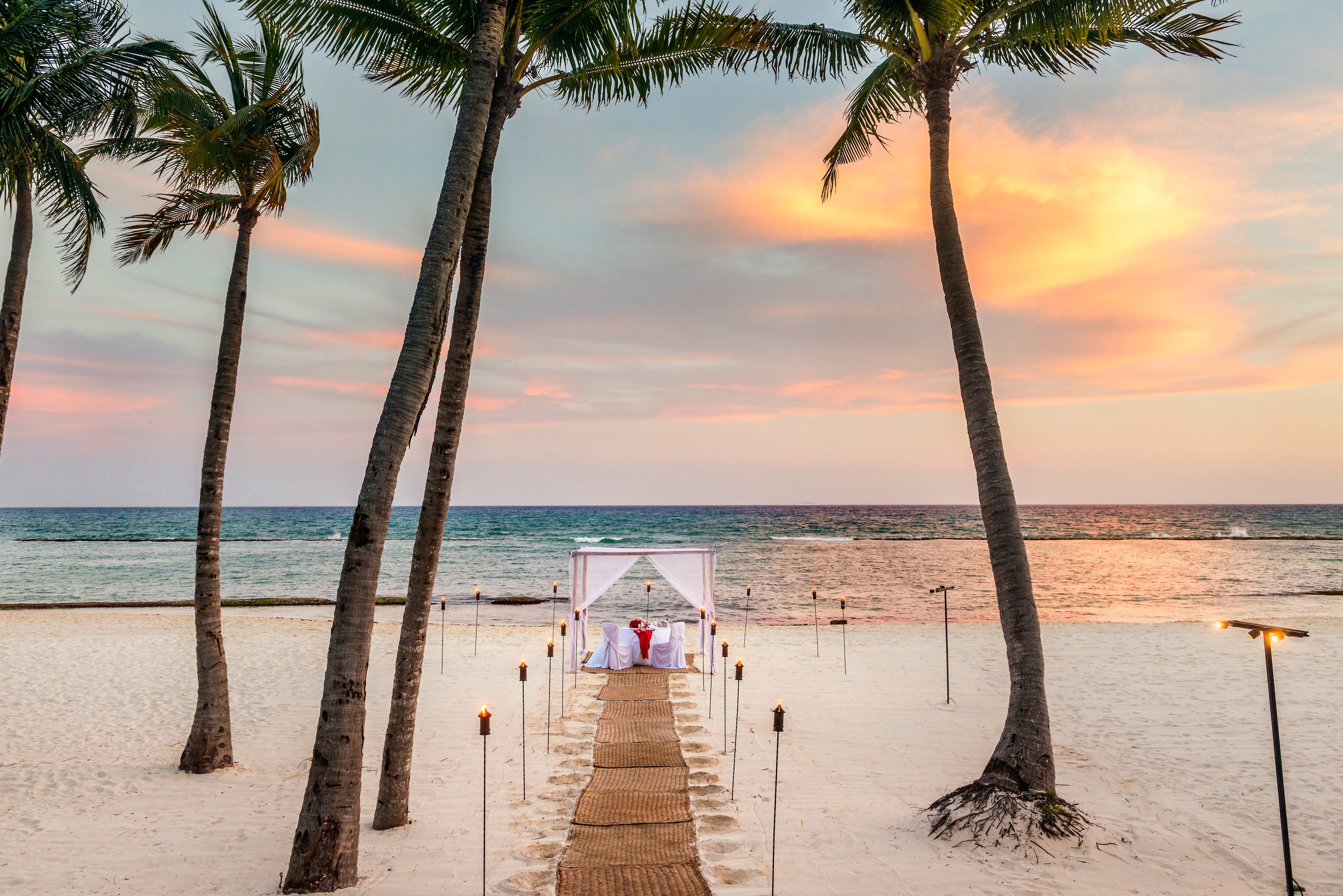 Ceremonia de boda en la playa rodeada palmeras al atardecer, Grand Velas Riviera Maya, Playa del Carmen, México