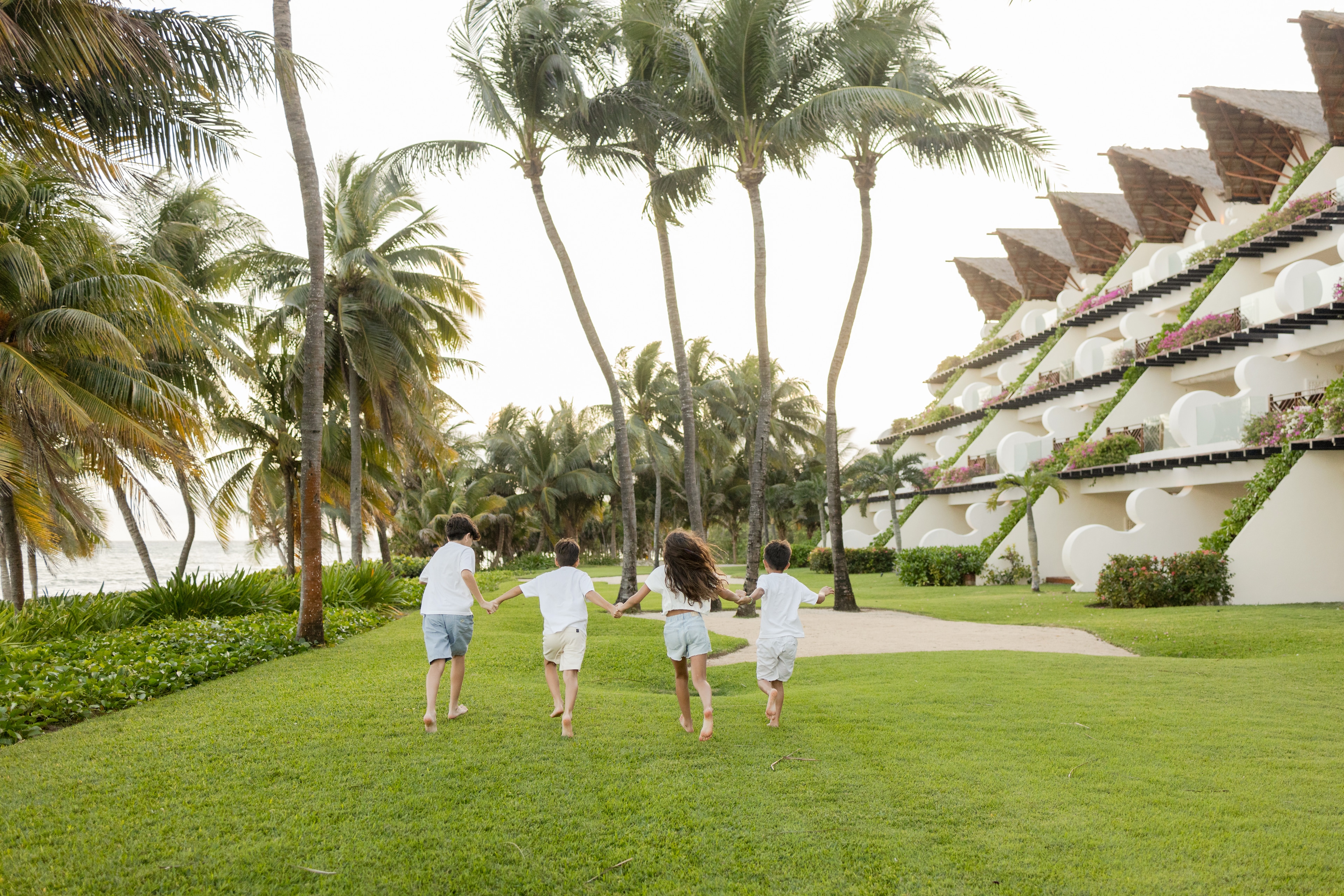 Three children running down the beach with palm trees, Grand Velas Riviera Maya, Playa del Carmen, Mexico