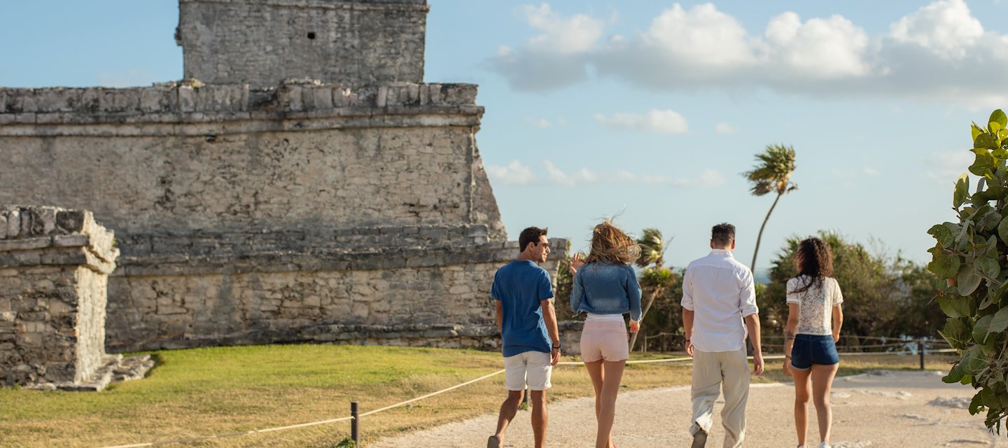 Four people walk towards a stone Mayan at Grand Velas Riviera Maya, Playa del Carmen, Mexico