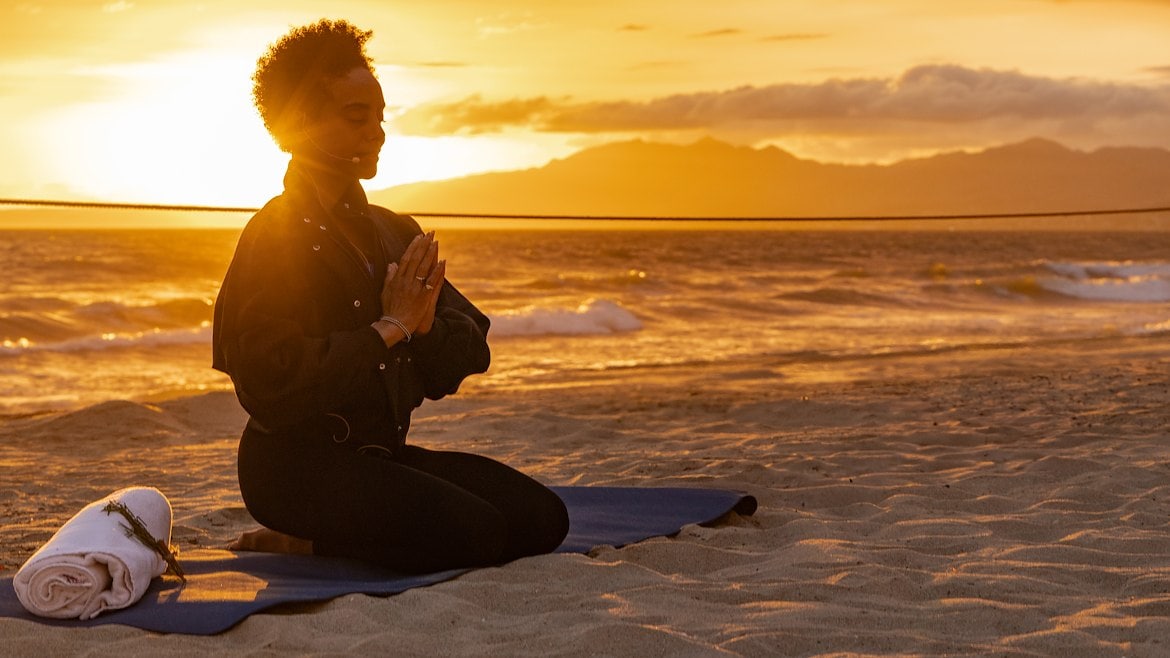 a woman meditating at sunset