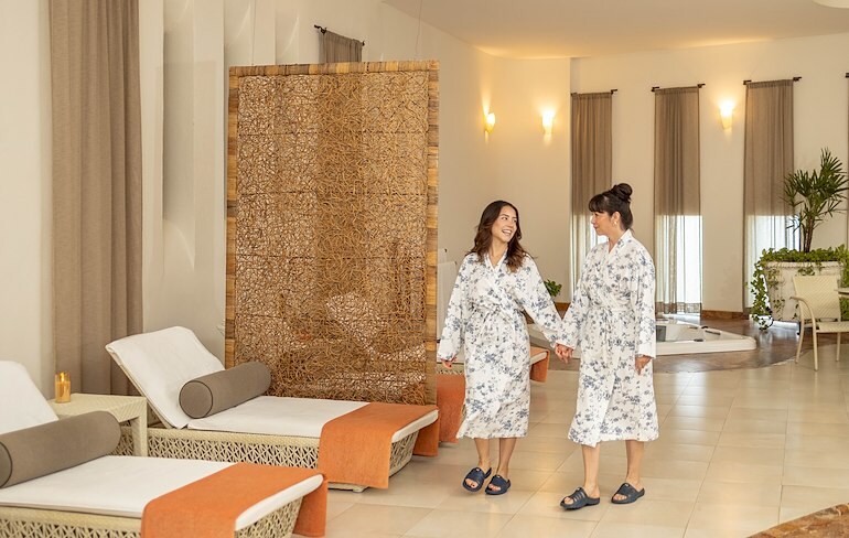 two women in robes waking in a spa