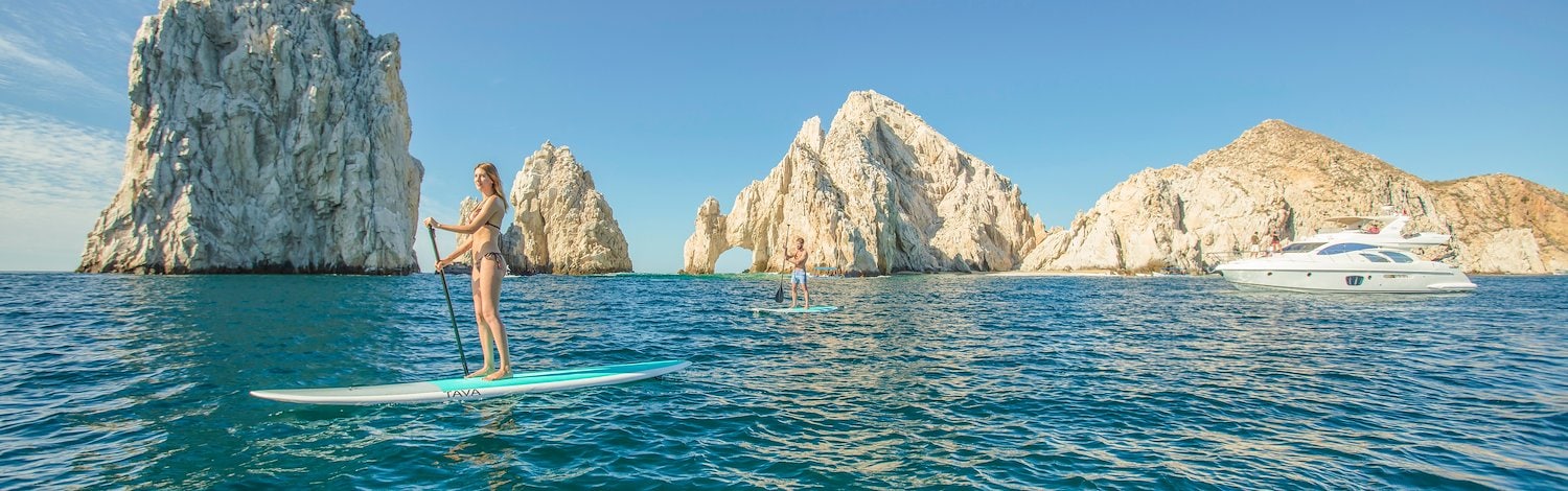 A woman on a paddle board in the ocean near some rocks, Grand Velas Los Cabos, San Lucas, Mexico