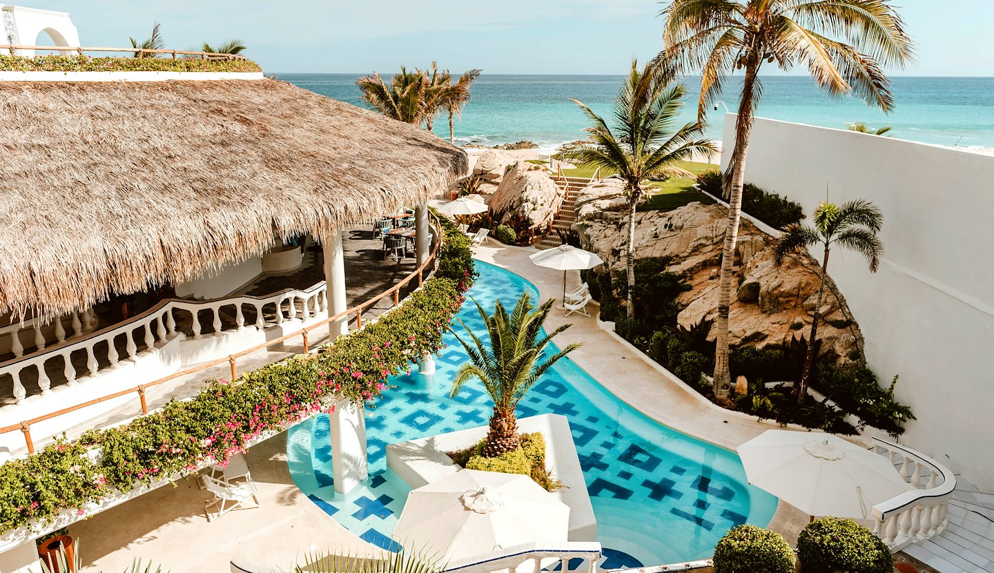Palm-lined pool with ocean view and Mediterranean architecture at Mar del Cabo, San Lucas, Mexico