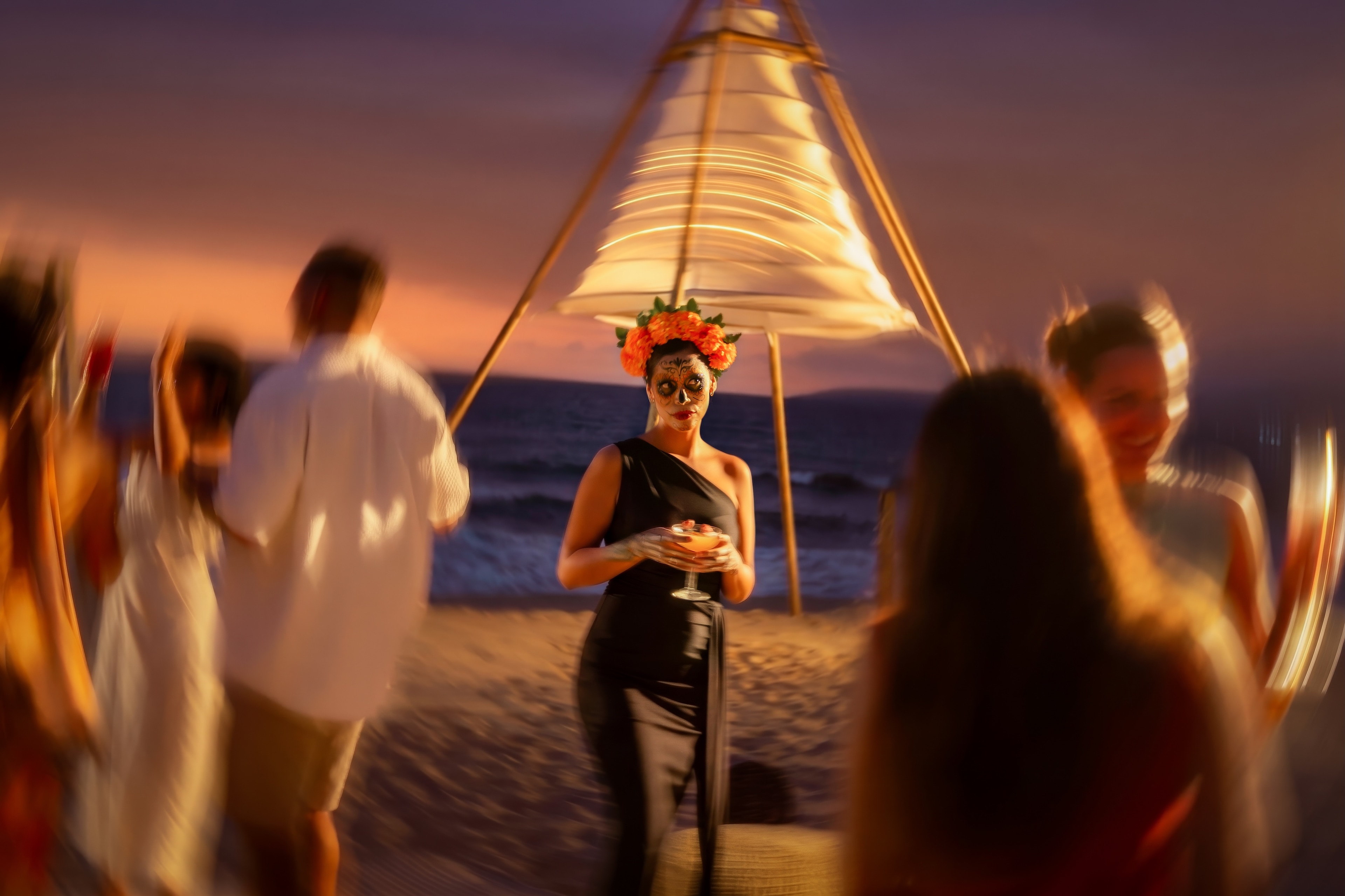 A woman with a flower crown and a hat on her head on a beach