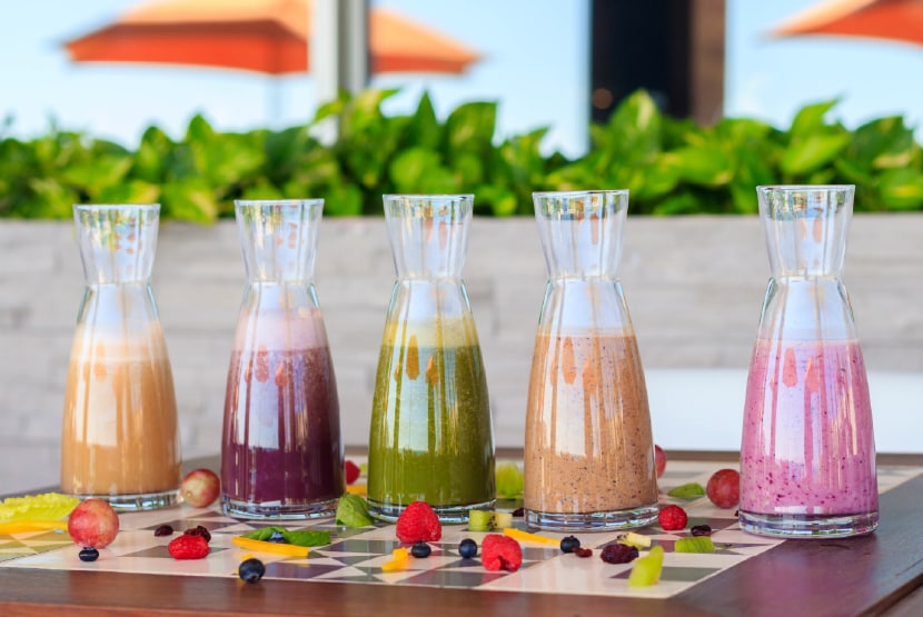 A group of glasses with different colored drinks on a table