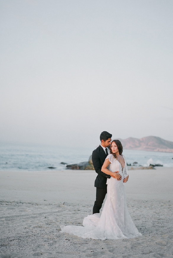 A man and woman in a white dress on a beach