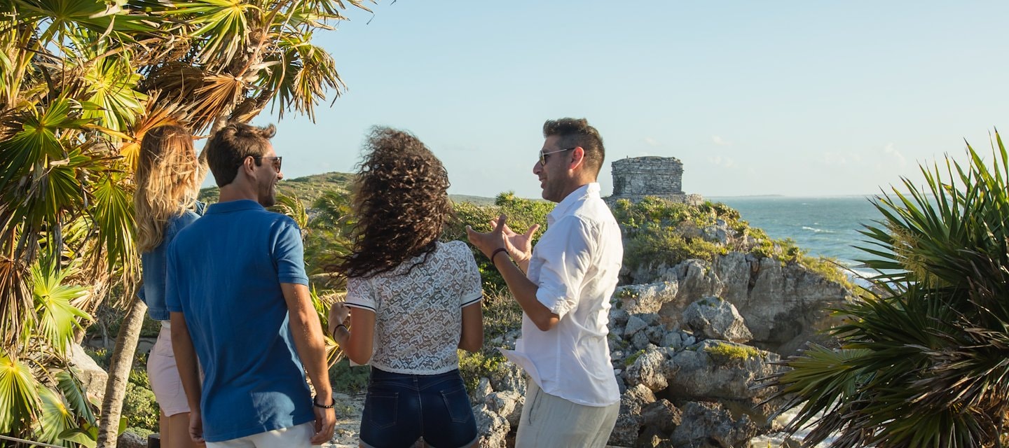 Tres personas de pie en un sendero rocoso junto al mar, Grand Velas Riviera Maya, Playa del Carmen, México