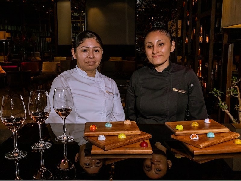 Two women sitting at a table with glasses of wine