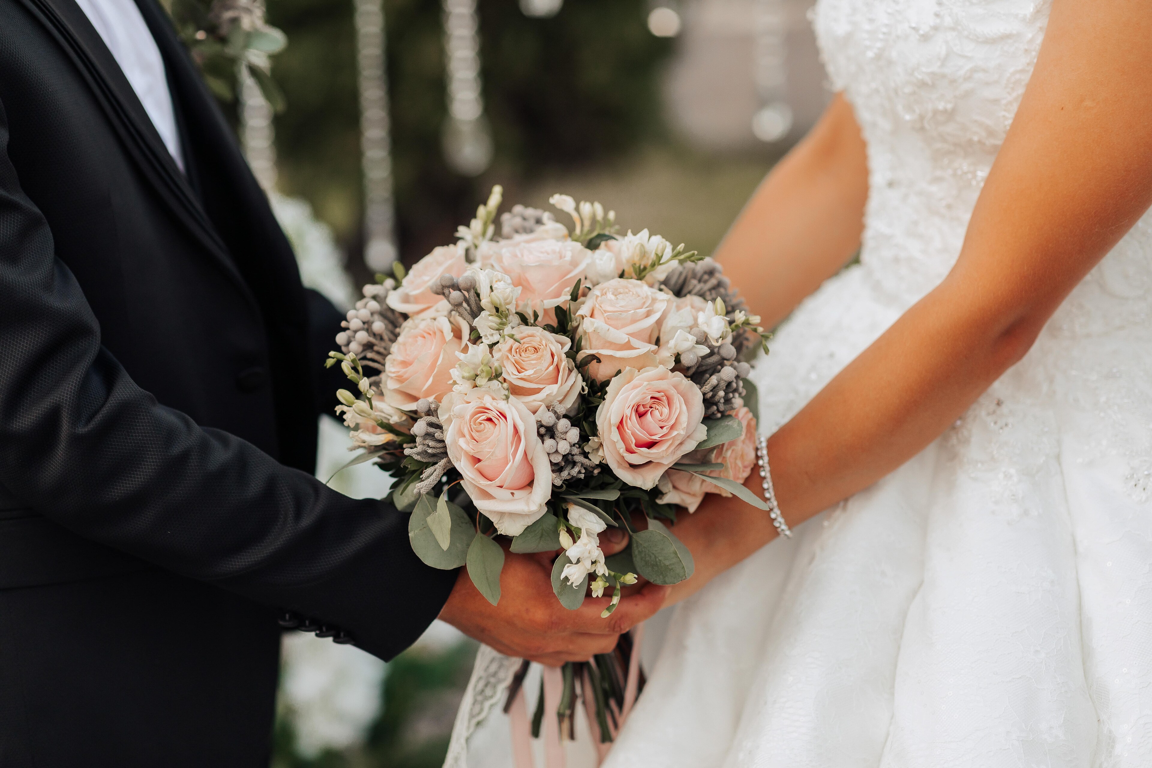 A bride and groom holding hands with a bouquet