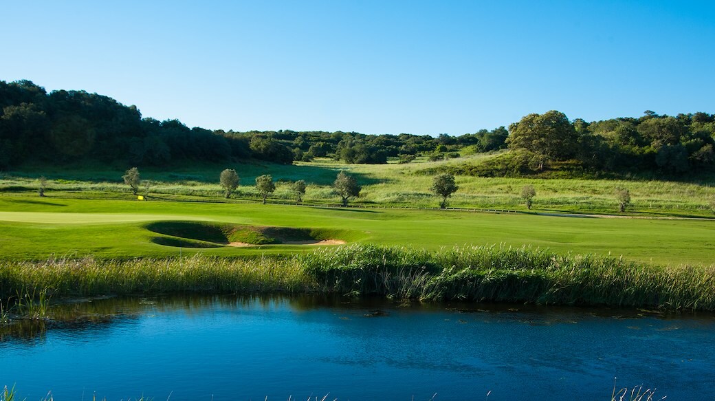 A Morgado Golf Course With a Pond in the Foreground at NAU Hotels & Resorts, Portugal