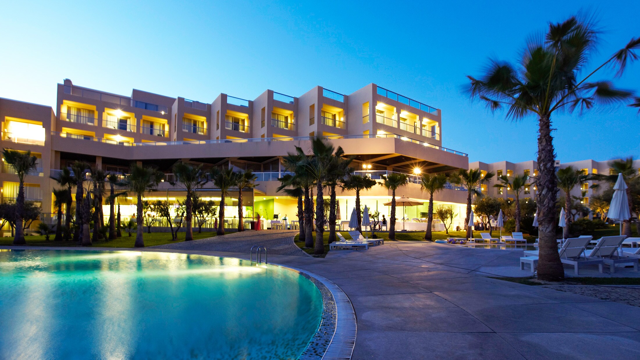 A pool and building with palm trees