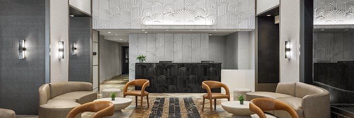 A hotel lobby with elegant decor, comfortable seating, and a reception desk At The Muse New York