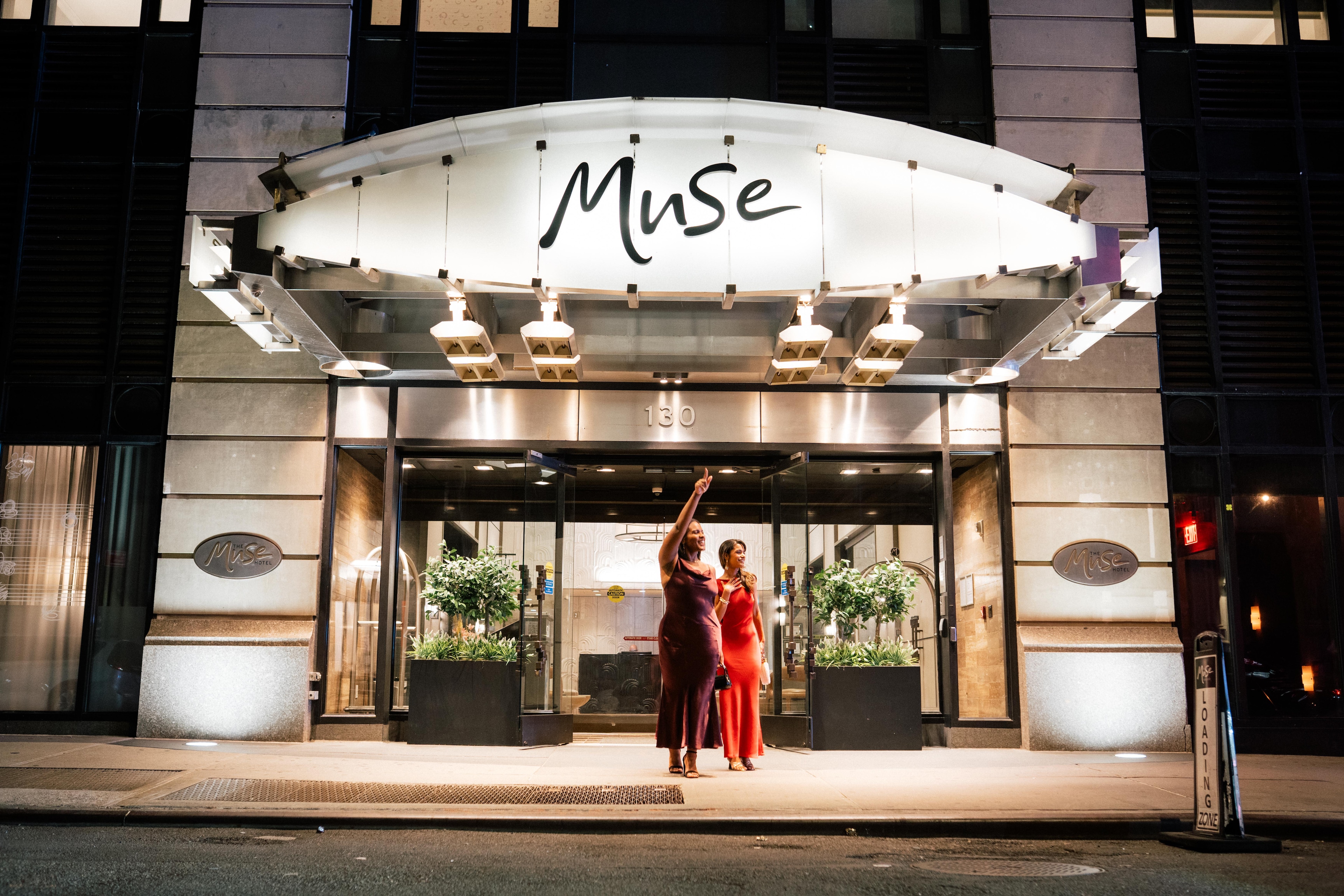 A group of women in red dresses outside the Muse Hotel of a building