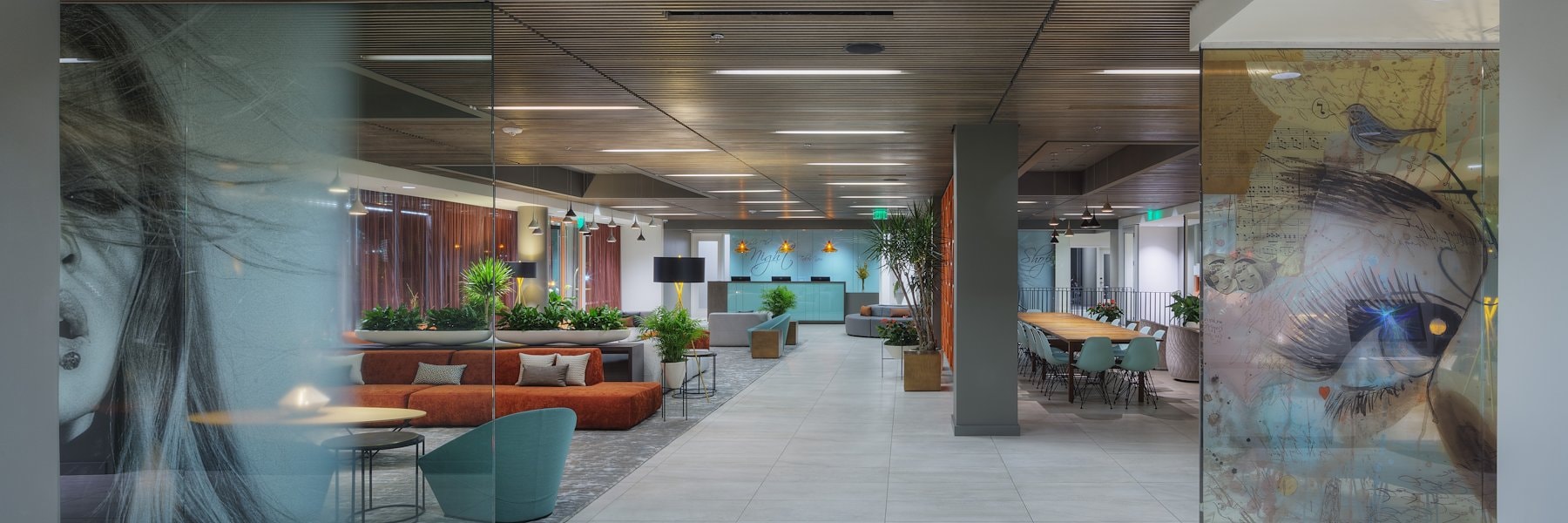 A modern hotel lobby with a seating area, artwork, and plants.