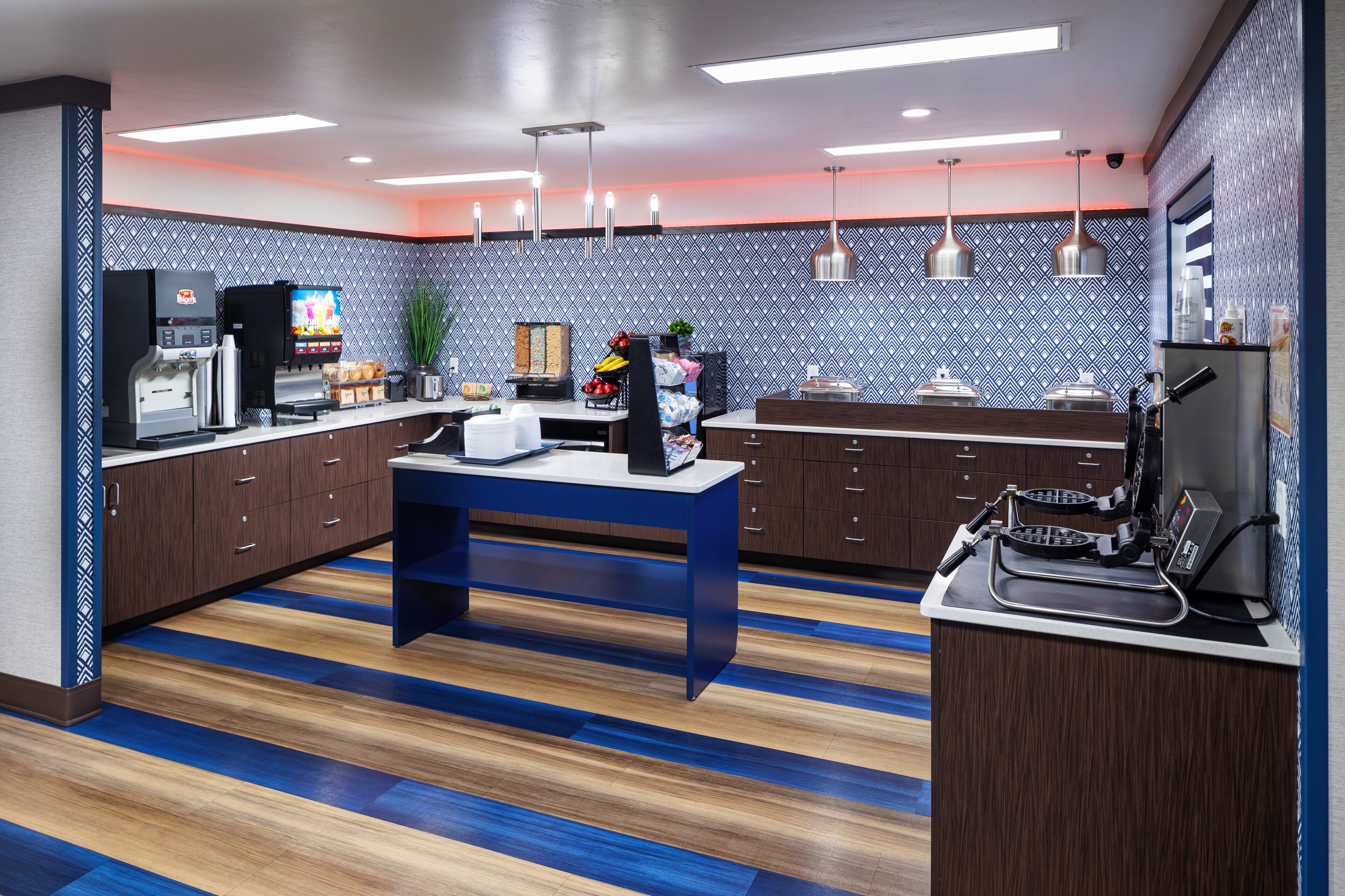 A hotel breakfast area with waffle makers, coffee, and food At Hotel J, Green Bay, Wisconsin
