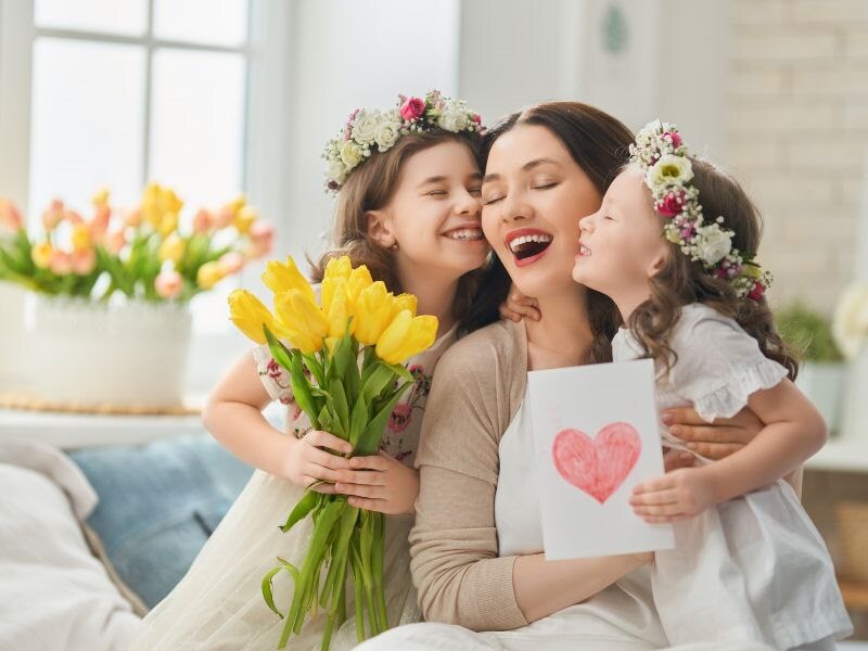 girls kissing mom with flowers
