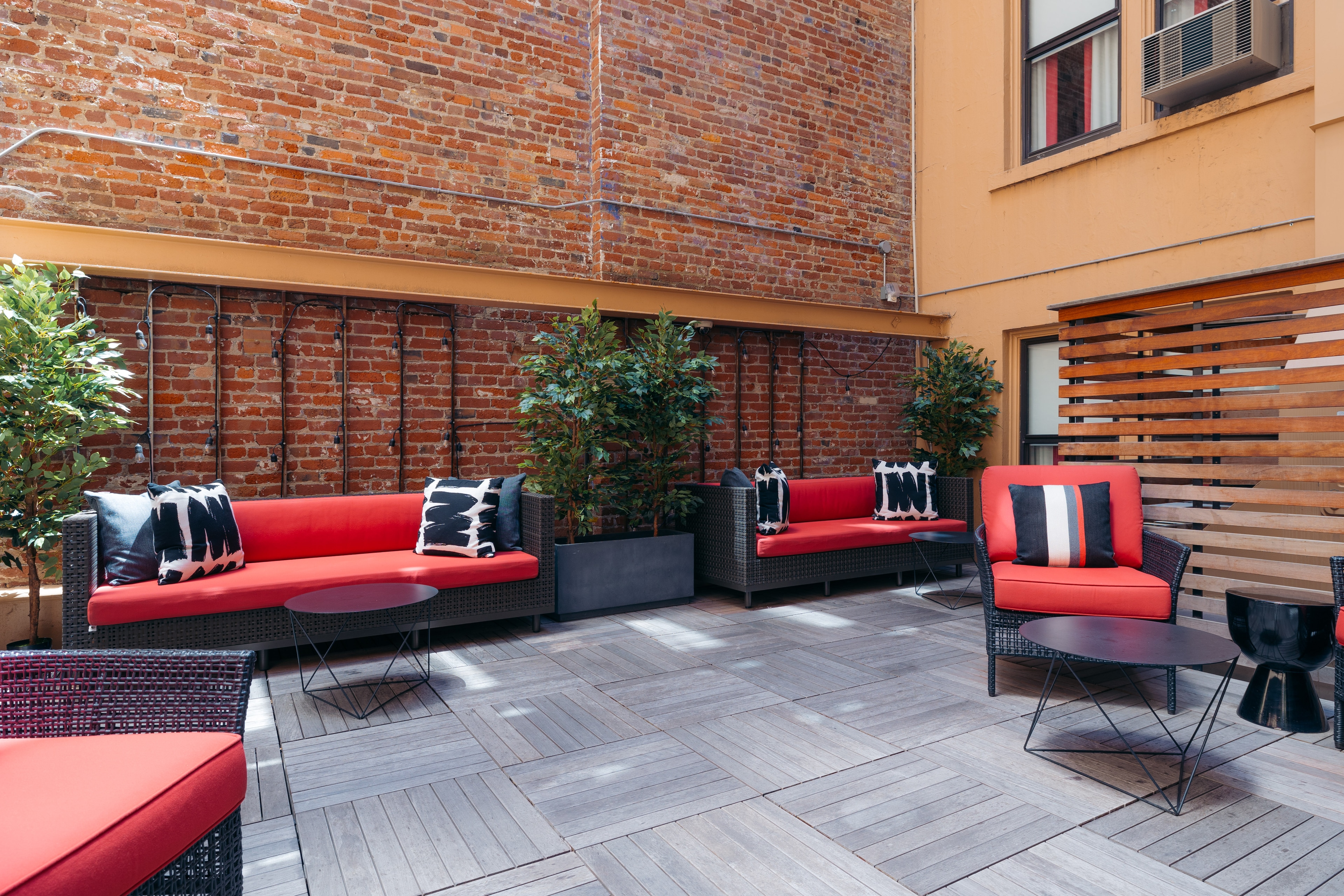 An outdoor seating area with red and black furniture and a brick wall.
