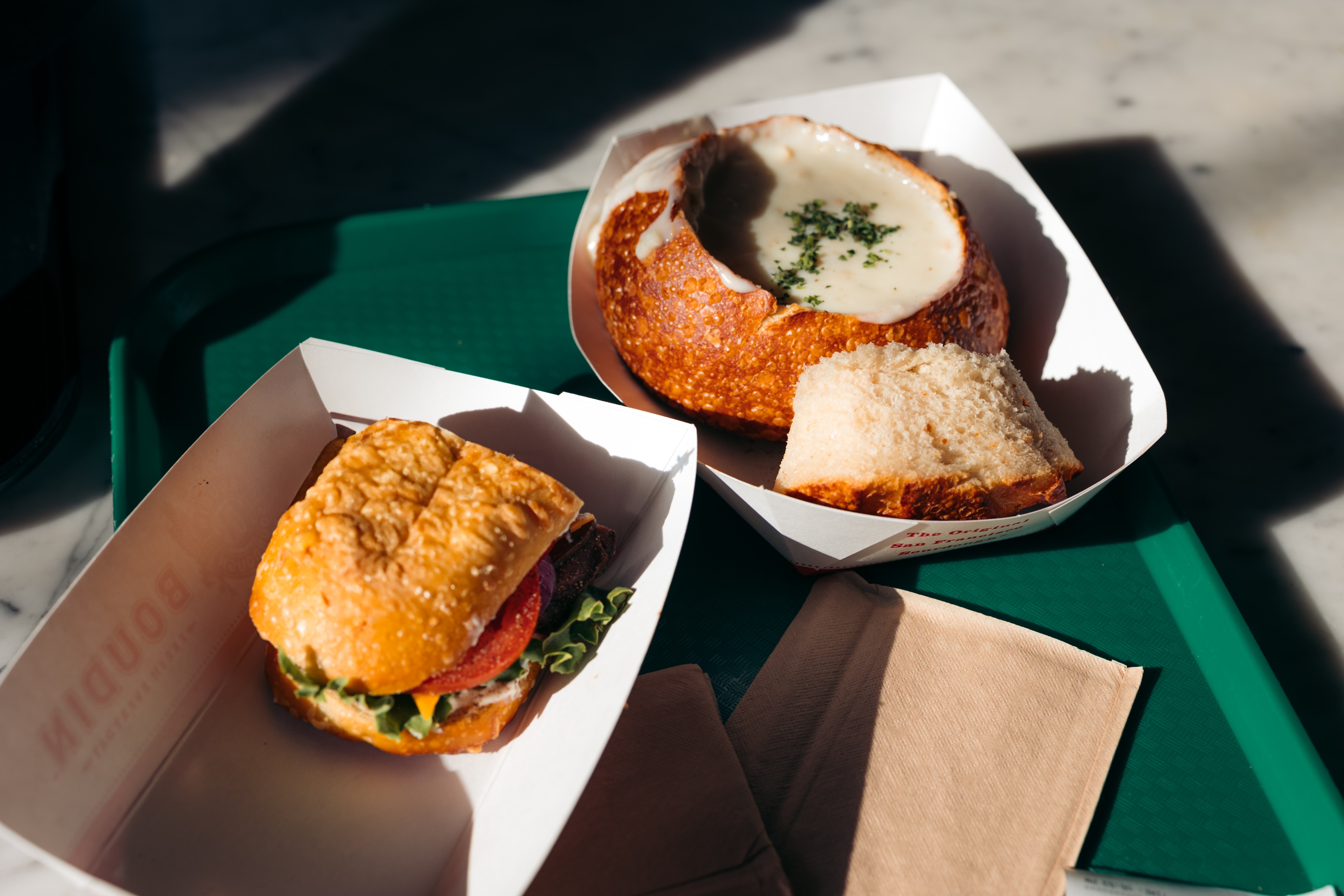 two paper containers with food on a green tray