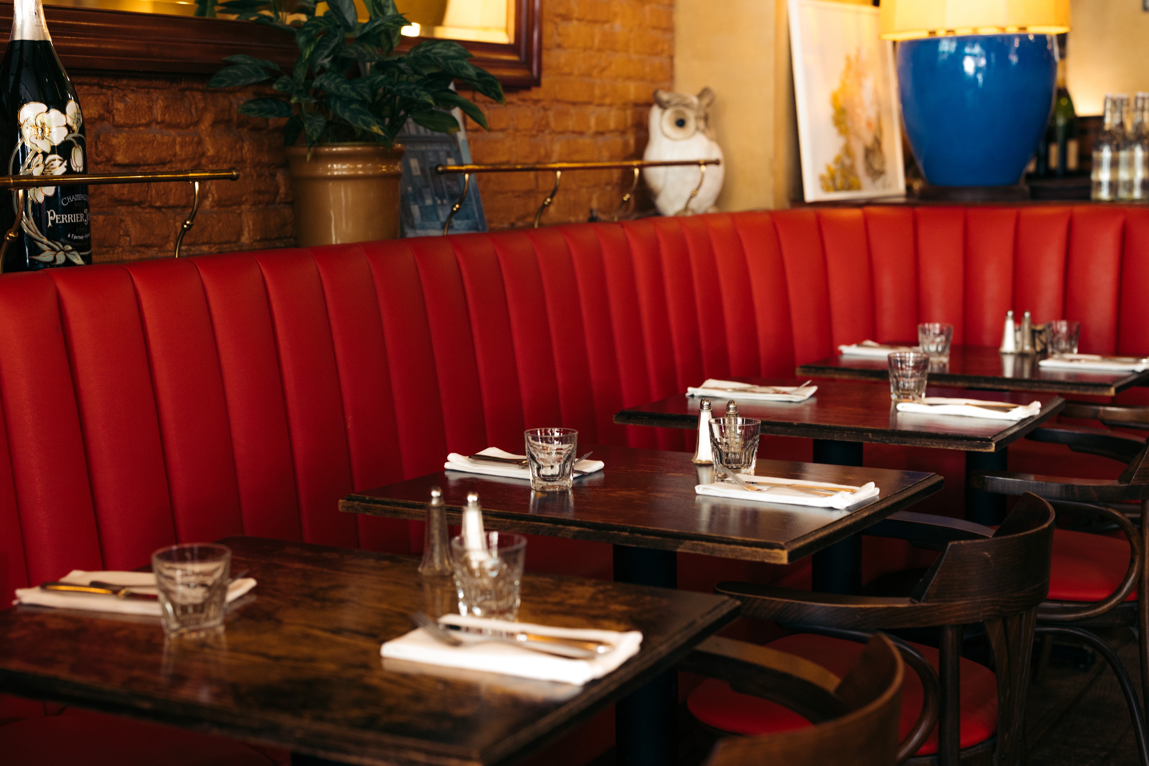 A restaurant dining area with set tables and red booth seating.
