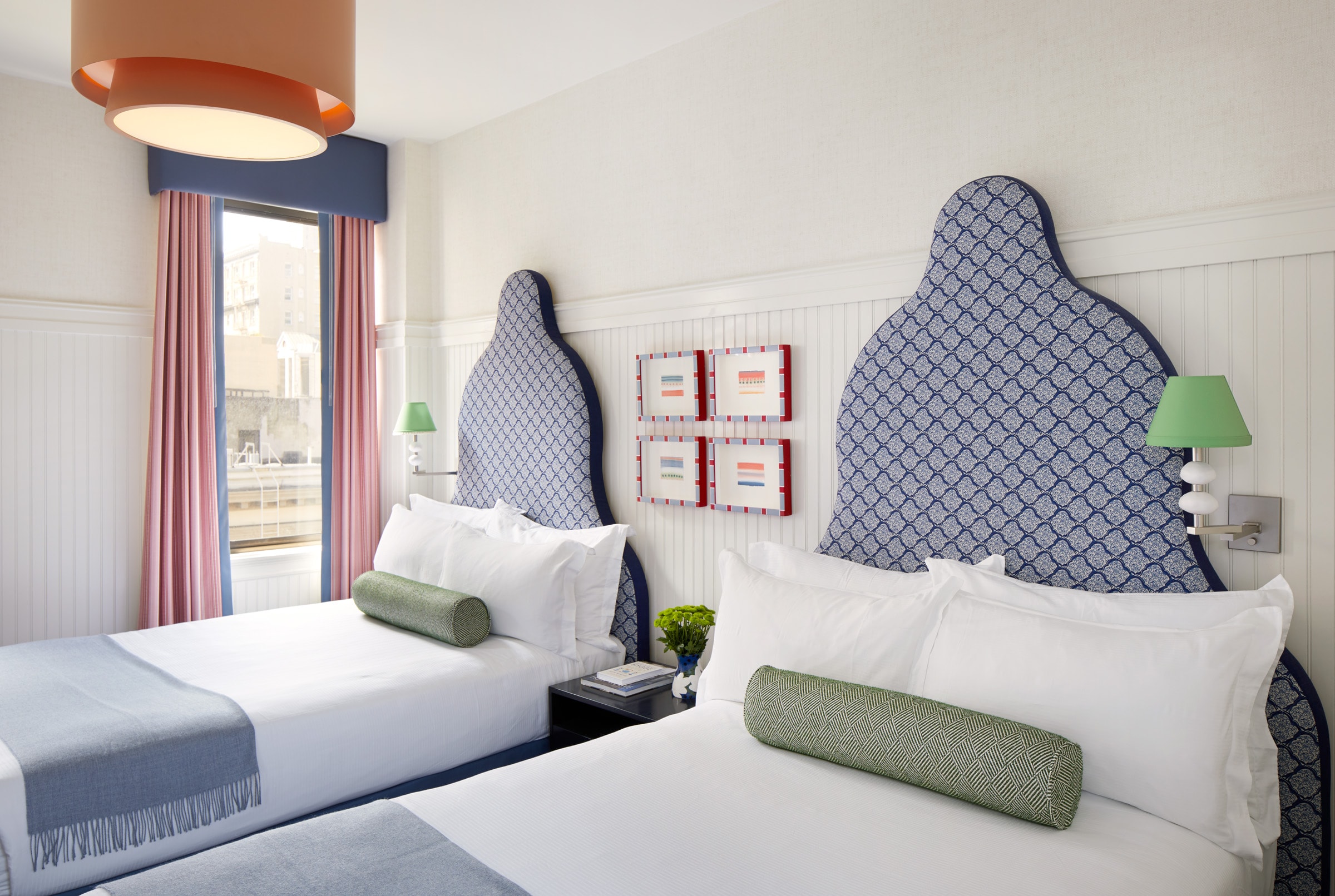 A hotel room with two twin beds, white bedding, and blue patterned headboards.