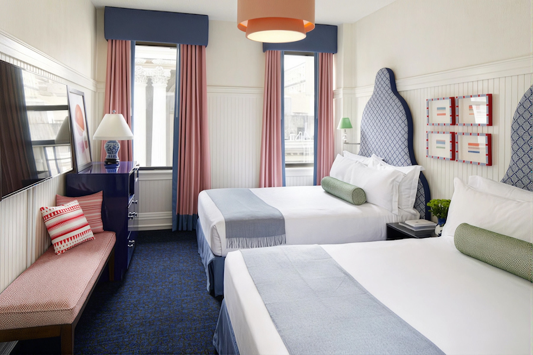 A wide view of a hotel room with two beds, a window, and furniture