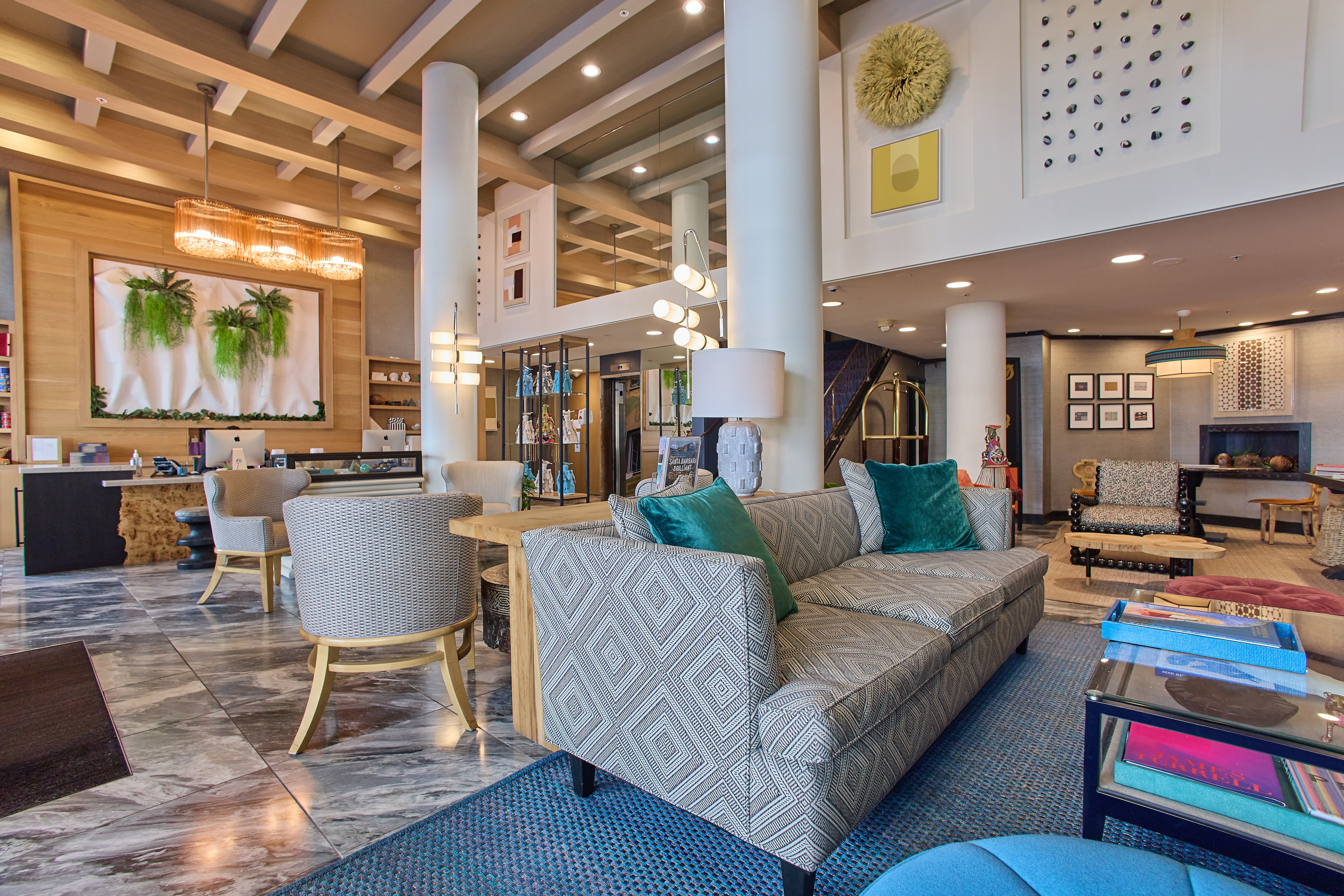 A spacious lobby with a sofa, coffee table, chairs, columns, and high ceiling.