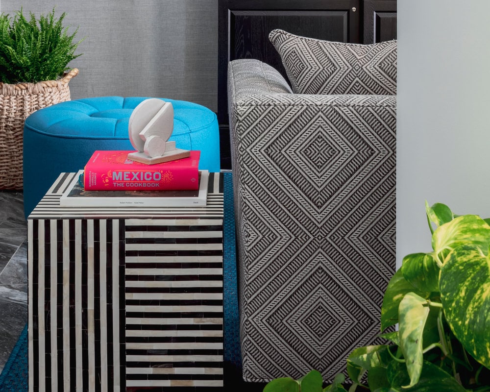 A hotel room with a bed, nightstand, and plants