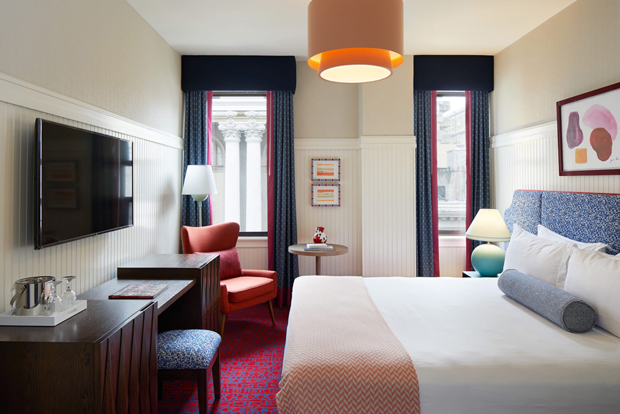 A hotel room with a bed, desk, chair, and TV.