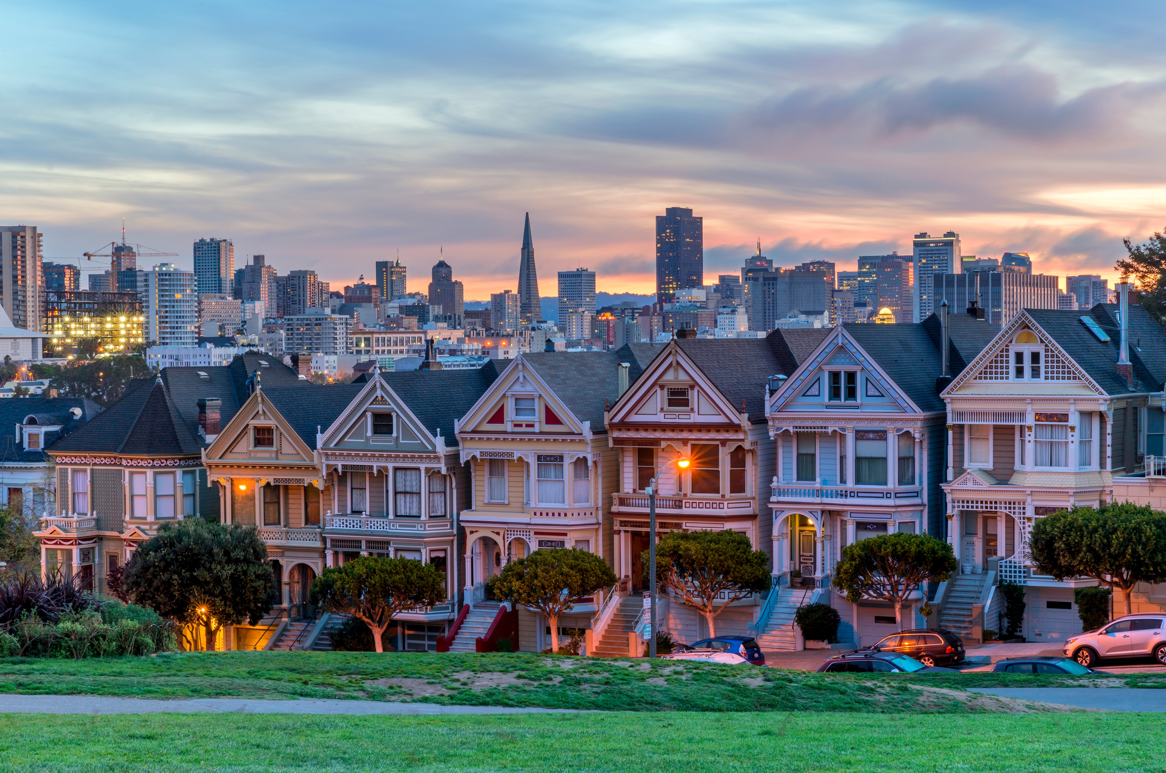 a row of houses with a city skyline in the background at sunset