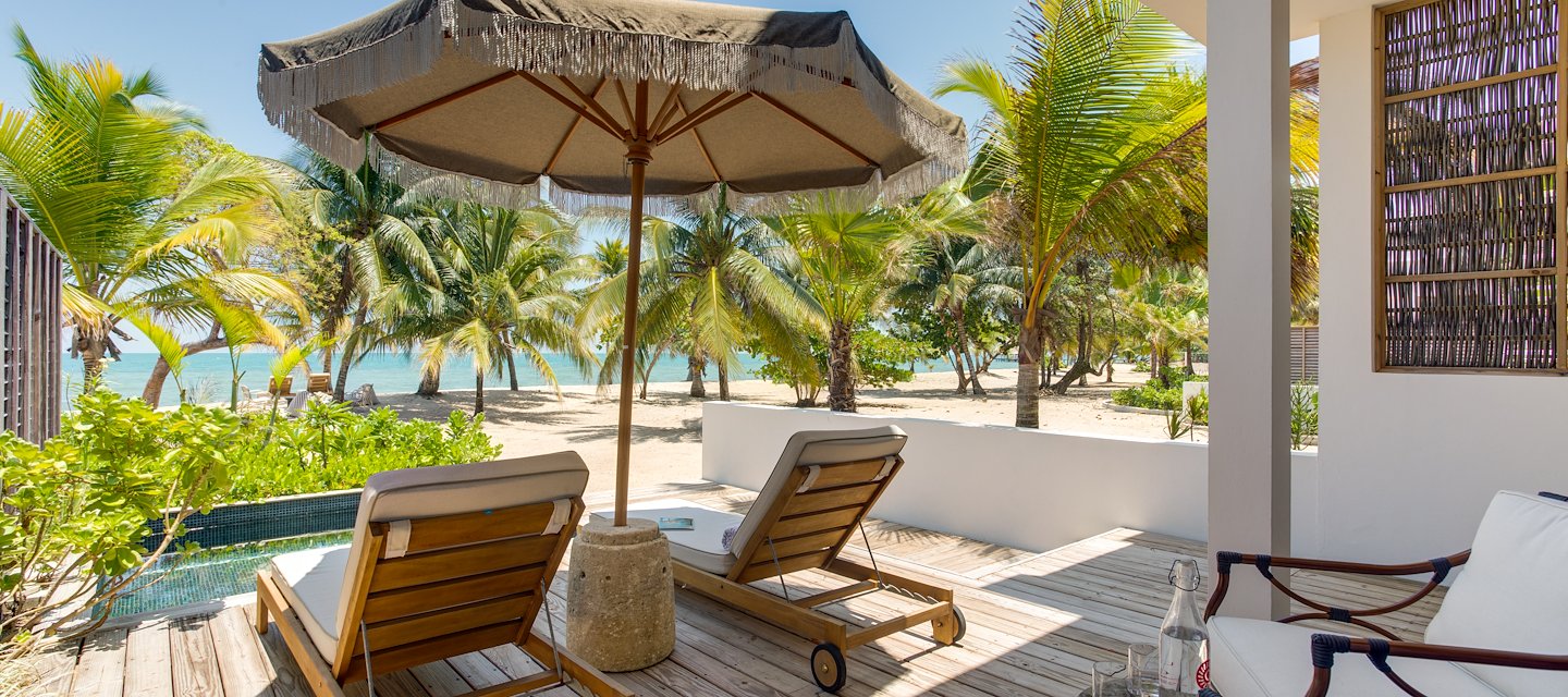 Beachfront villa deck with lounge chairs at Itz’ana Belize Resort in Placencia, Belize